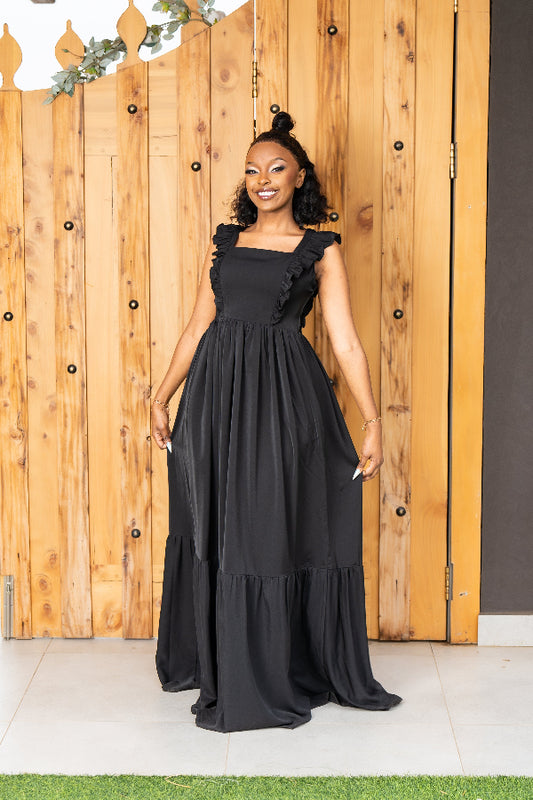 Woman wearing a black dress standing in front of a wooden fence.