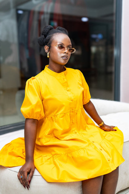 Woman in a yellow dress sitting on a white couch with a blurred background