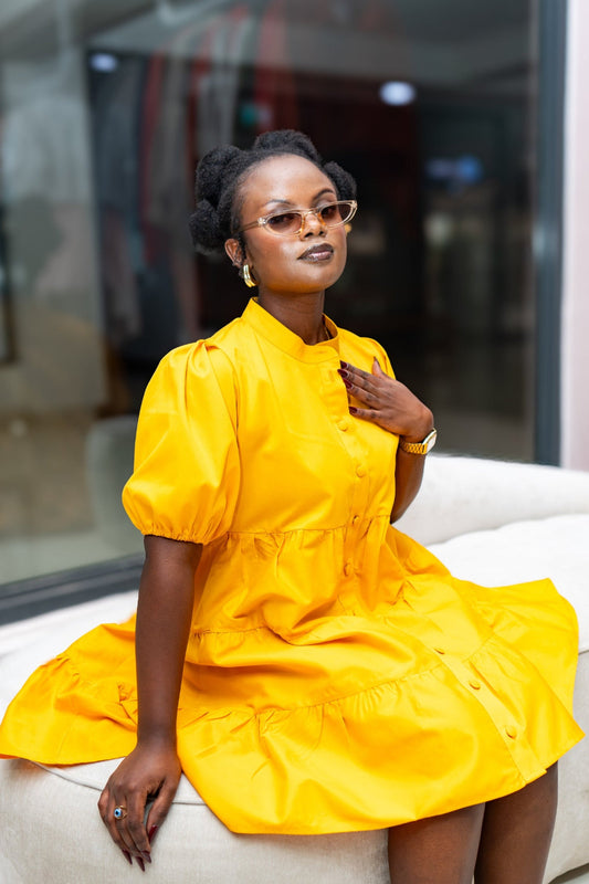 Woman in a yellow dress sitting on a white couch with a blurred background